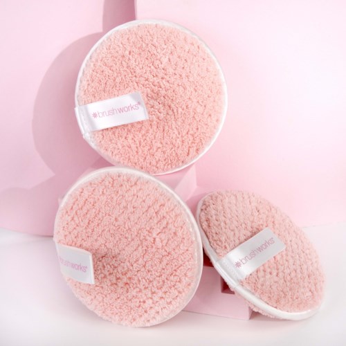 Three fluffy pink cleaning scrubbers with tags, set against a pink background.