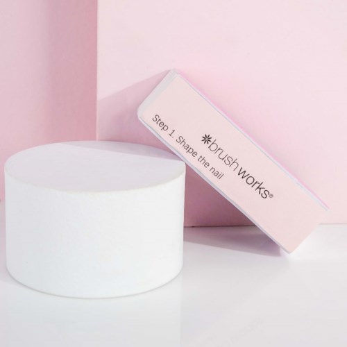 A pink box labeled 'Step 1 Shape the nail' and a white round container on a white surface.