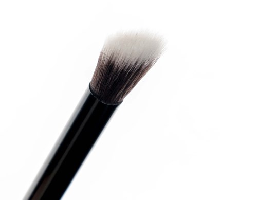 Close-up van een make-up kwast met witte en zwarte haren op een witte achtergrond.