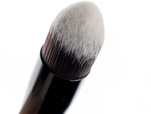 Een make-up kwast met een witte, pluizige top en een donker handvat.