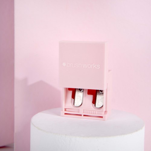 A pink device on a white stand has the words 'blush works' on it and two metal parts inside.