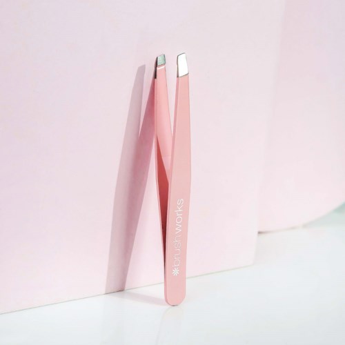 Two pink tweezers with silver tips stand against a pink background. The tweezers are labeled 'DUSH WORKS'.