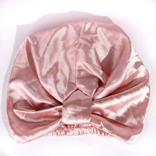 A soft, pink satin head wrap with a large bow and elastic band inside. Smooth and shiny fabric.