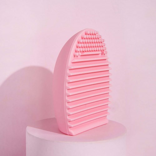 Roze verzorgingsborstel met kleine borstelharen boven en brede ribbels eronder, staat op een pasteloppervlak.