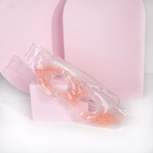 A clear plastic object with pink beads inside, set against a pink background, appears to be a decorative or cosmetic item.