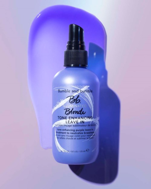 A purple bottle with a black spray cap, labeled Bumble and Bumble Blonde Leave-In treatment, against a purple background.