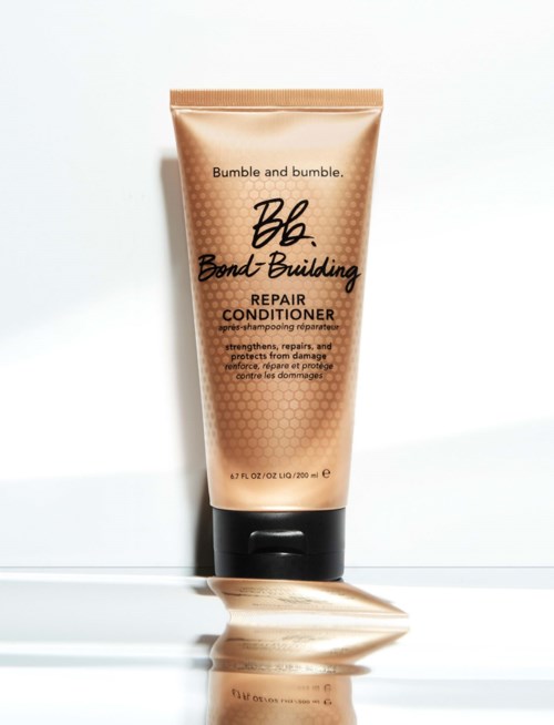 Bumble and bumble Repair Conditioner Tube steht auf flacher Oberfläche, aufrecht, mit etwas Produkt daneben.