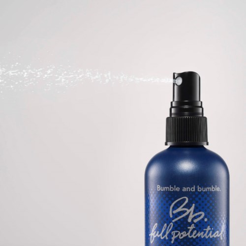 Eine blaue Sprühflasche mit "Bumble and bumble" Beschriftung und Sprühkopf, der Nebel versprüht.