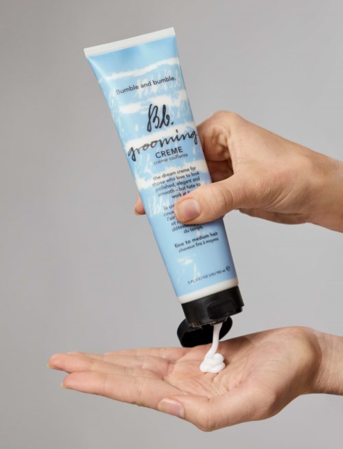 Eine Hand hält eine blaue Tube mit Bumble and Bumble Pflegecreme und gibt weiße Creme auf die Hand.