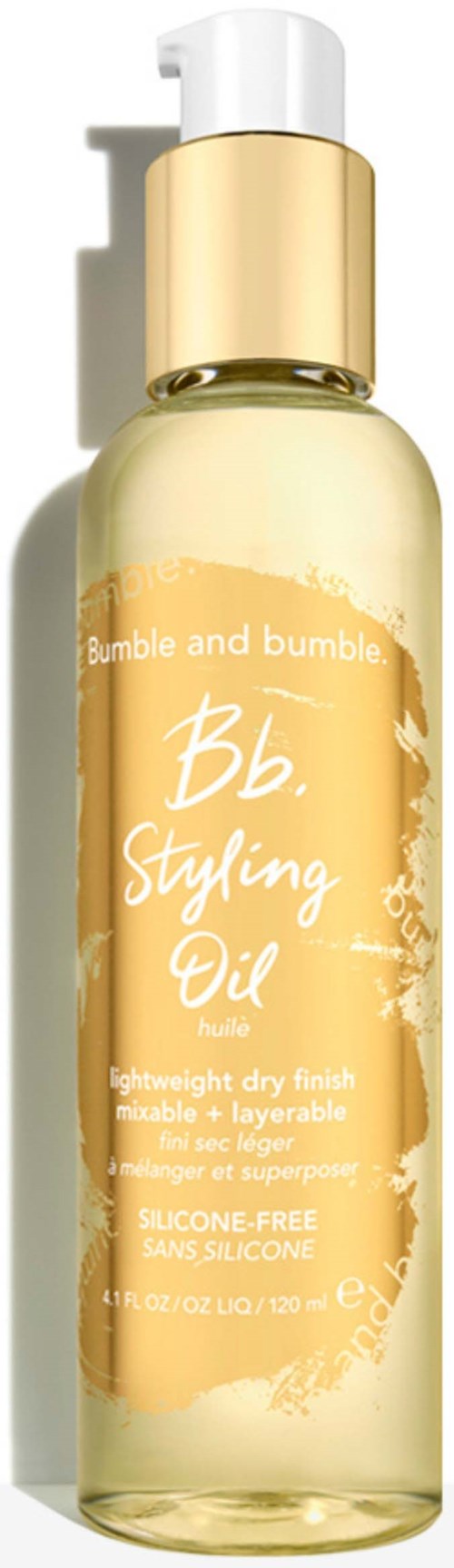 A clear bottle with a white pump, gold cap, and orange label containing text about styling and silicone-free oil.