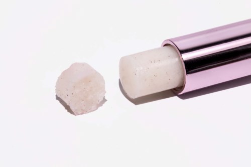 A pink and silver device is used to make white, round, textured soap or bath bomb. The bomb is shaped and ready.