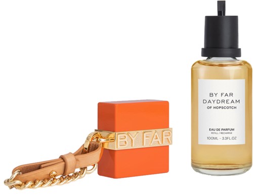 A perfume bottle with a dropper, orange soap, and a pink strap with gold lettering. Elegant and stylish items.
