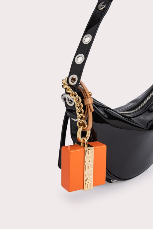 A black bag with a strap and an orange keychain with a chain attached.
