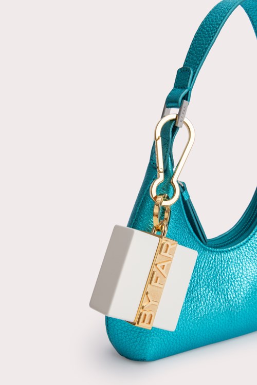 A bright blue handbag with a gold and white lock charm hanging from a strap.