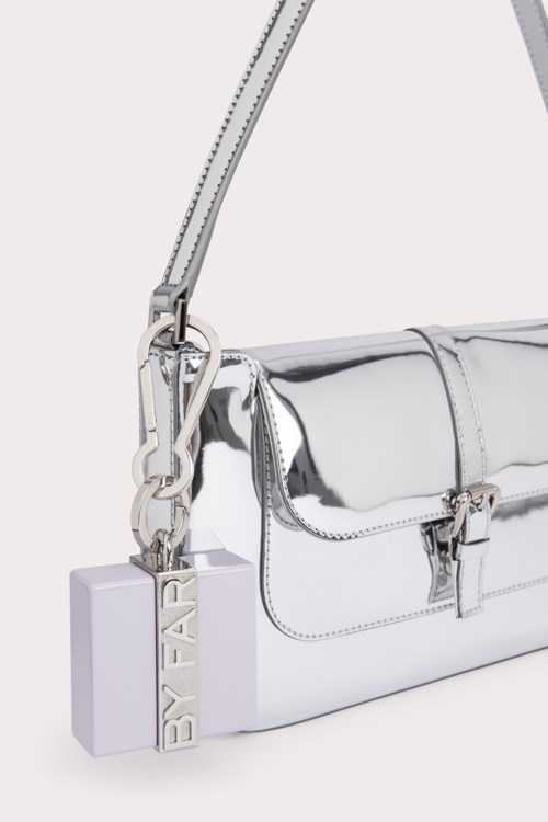 A shiny silver bag with a strap and a white tag saying "BY FAR."