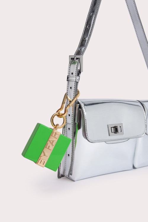 A silver handbag with a strap and a lock, with a green and gold keychain attached.