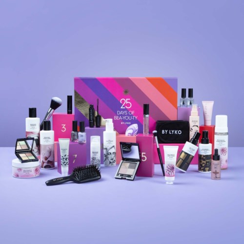 Ett skönhetsprodukter med olika krämer, spray, brushes och makeupartiklar arrangerade framför en färgglad box.