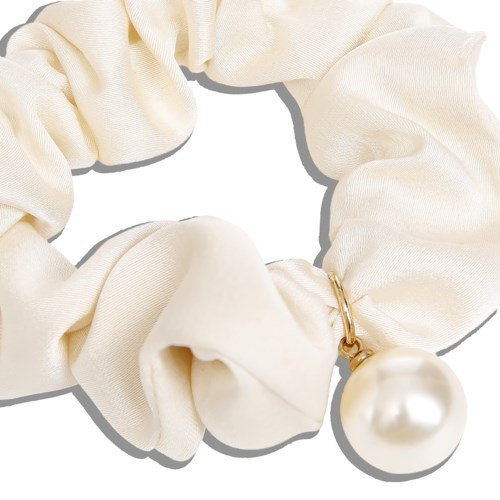 A cream-colored fabric scrunchie with a large pearl charm.