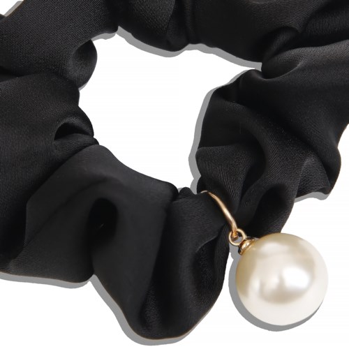 A black fabric scrunchie holds a large white pearl pendant, creating a stylish jewelry accessory.
