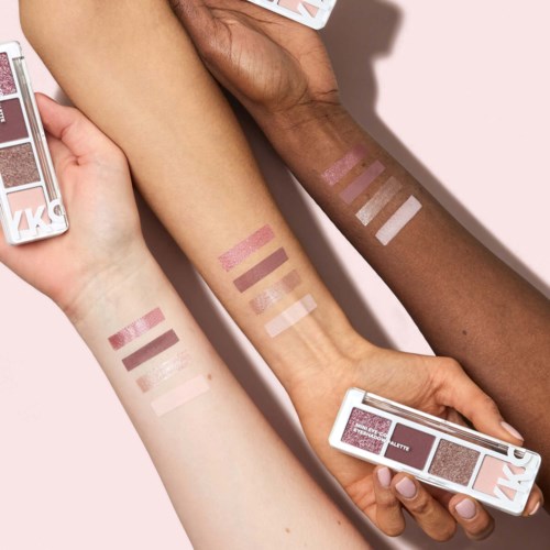 Drie armen met verschillende huidskleuren tonen swatches van roze, bruin en wit make-up en make-uppaletten.