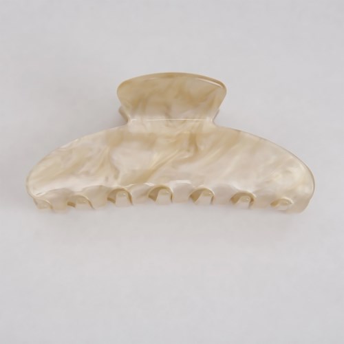 A large, beige hair clip with a wavy, ridged design sits on a light background.