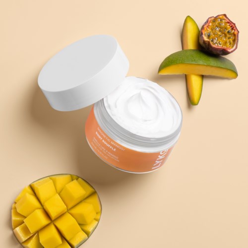 Een potje witte crème met mango en passievrucht ernaast op een beige achtergrond.