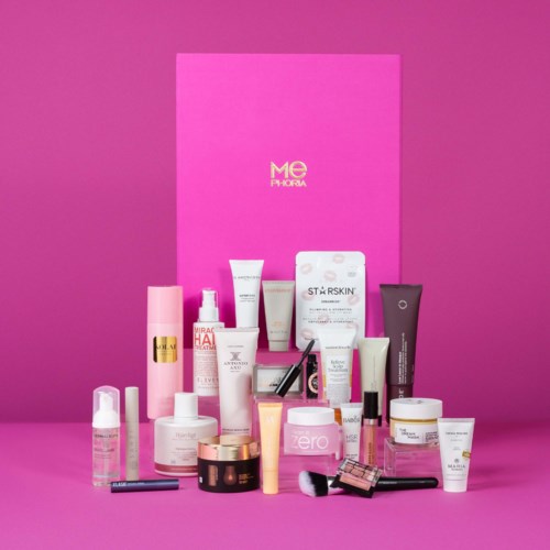 En rosa presentlåda bakom olika hudvårds- och makeupprodukter på rosa bakgrund.