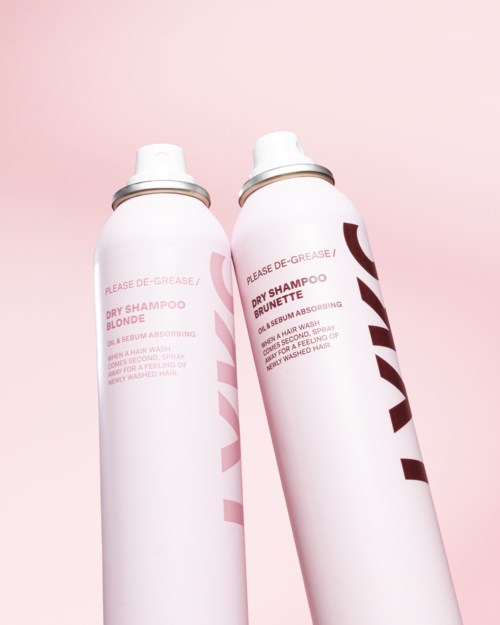 Two white shampoo cans with red and black writing against a pink background.