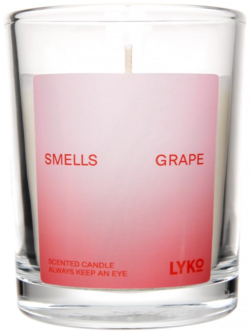 Tuoksukynttilä, jossa lukee 'Smells Grape', punaisella ja vaaleanpunaisella tekstillä, kirkkaassa lasikuvussa.