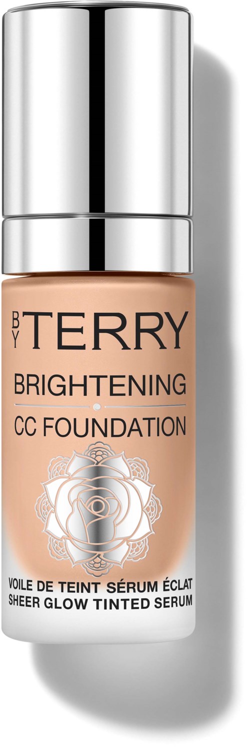 A bottle of BY TERRY Brightening CC Foundation with a silver cap and peach-colored liquid inside.