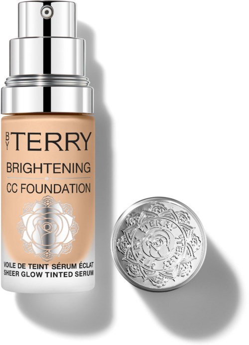 A bottle of brightening CC foundation and a silver compact with embossed design. The bottle has a pump and is labeled.