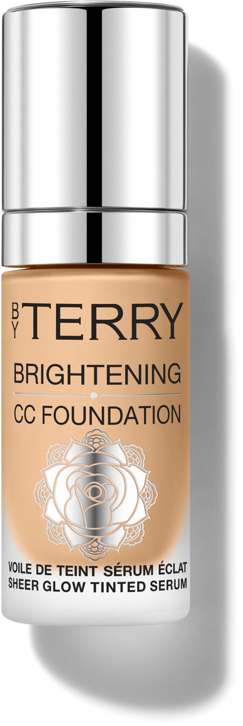 A bottle of BY TERRY Brightening CC Foundation with a silver cap, beige liquid inside, and floral design on the label.