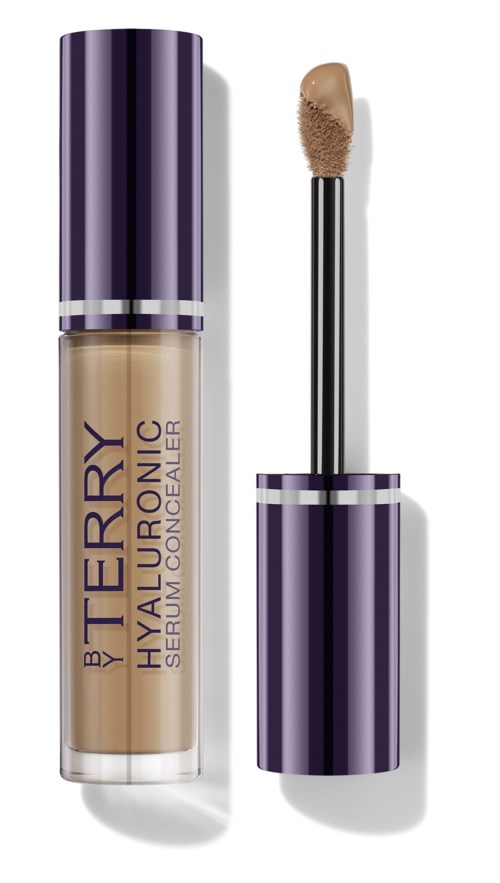 Peitevoidepullo, jossa on violetti ja hopea muotoilu, teksti 'BY TERRY Hyaluronic Serum Concealer', sovellusruisku näkyy.
