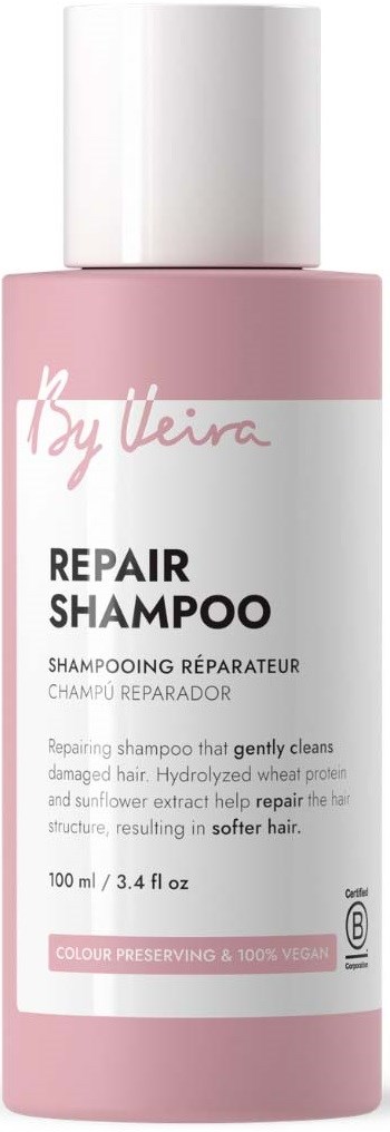 Lys rosa flaske med Repair Shampoo og hvitt lokk, etikett som sier den forsiktig rengjør skadet hår og er vegansk.