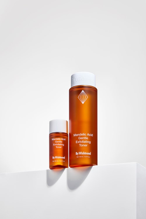 Zwei orangefarbene Flaschen mit Hautpflegeprodukten mit weißen Verschlüssen, gekennzeichnet als Mandelic Acid Toner von Wishtrend, auf einer weißen Oberfläche.