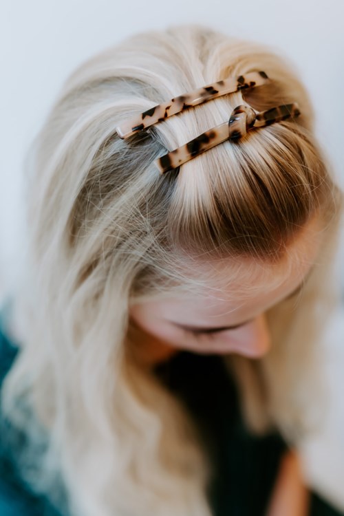 Blondes Haar mit zwei braunen Haarspangen auf der Oberseite, von oben gesehen.