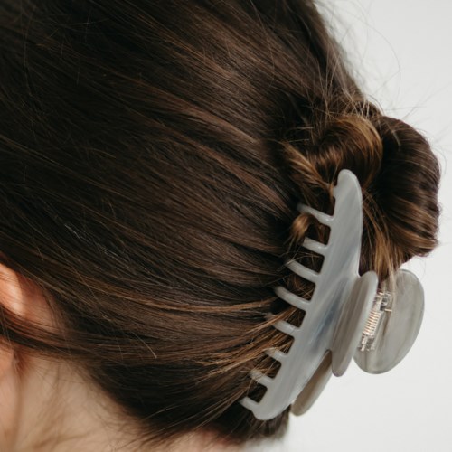 A person has their brown hair up in a bun, held by a large gray hair clip close to the scalp.