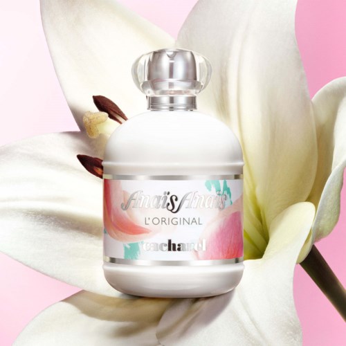 A perfume bottle labeled 'Amais Anais' surrounded by white lily flowers on a pink background.