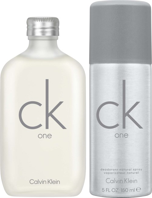 A white Calvin Klein CK One fragrance bottle with a silver cap and a silver deodorant spray can with a gray cap.