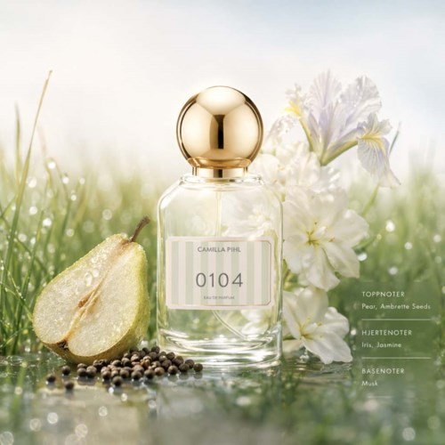 Een parfumfles met label Camilla Piu, met peren, jasmijn en musk, omgeven door peren en bloemen op een groene ondergrond.