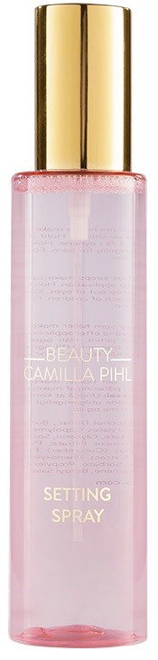 Een roze fles met een gouden dop met setting spray van Camilla Pihl.