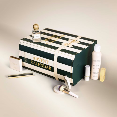 A large black and white striped advent calendar box with a ribbon, surrounded by perfume, skincare, and beauty products.