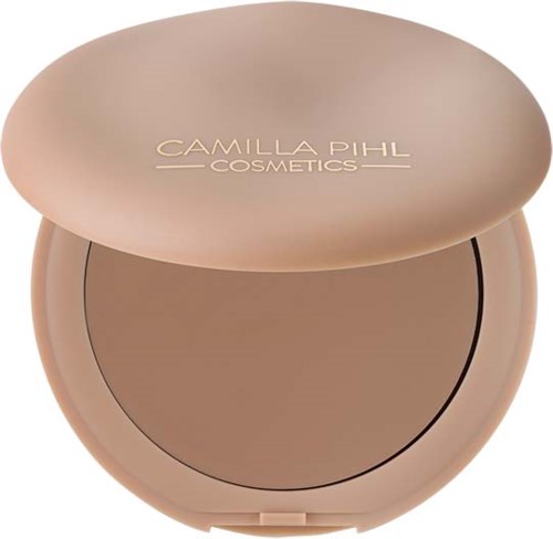 Ein runder Make-up-Deckel mit beigem Gehäuse, geöffnet, um hellbraunes Puder zu zeigen, beschriftet Camilla Pihl Cosmetics.