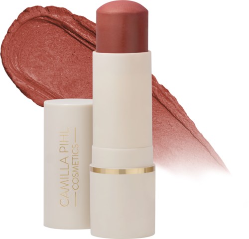 Ein Lippenstift mit beiger Verpackung und goldener Verzierung, dahinter ein rotbrauner Strich.