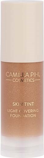 En fondationsflaska med ljusbrun färg, märkt 'Camilla Pihl Cosmetics Skin Tint.'