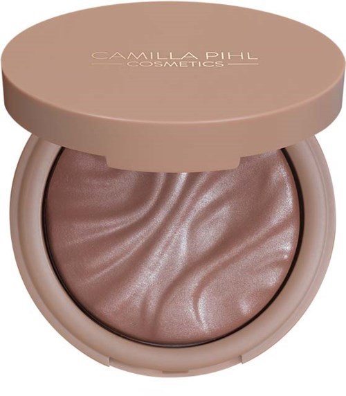 Een compact make-upproduct met een krullende, glanzende beige poeder erin, en een lichtroze deksel met tekst.