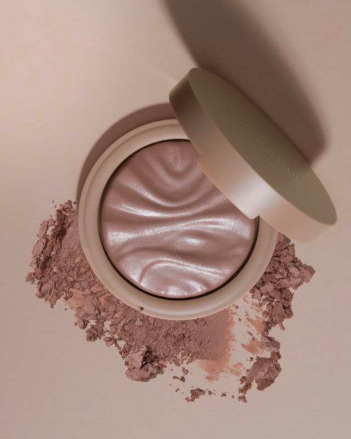 Een ronde container met glanzende roze make-up met wat poeder eromheen.