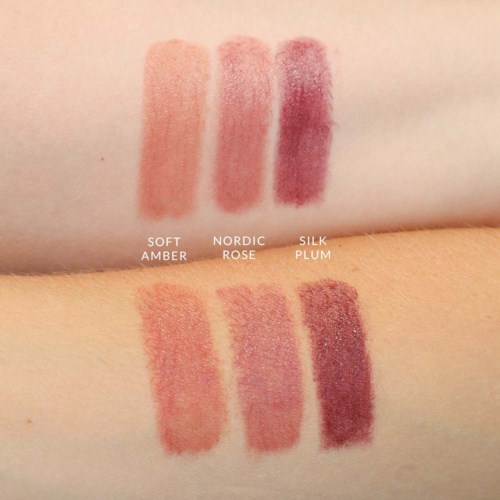 Smakeprøver av sminke i tre nyanser: soft amber, Nordic rose og silk plum, på hud med ulike toner.