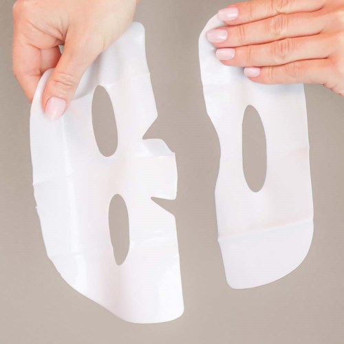 Two hands hold face mask pieces with cutouts, possibly for skincare or cosmetic use.