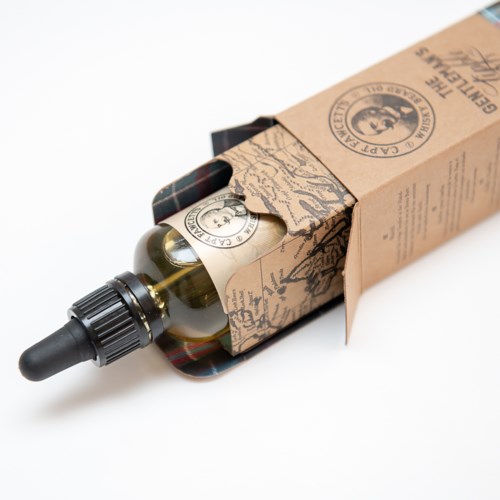A small glass bottle with a dropper cap, inside a brown box. The box has a vintage style with text and logo.